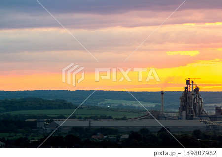 Yellow sunset over industrial landscape with factory chimneys and pipes with smoke polluting the atmosphere. 139807982