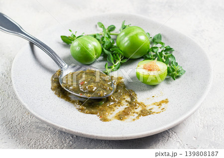 a spoon with tkemali sauce, on a plate, with cherry plum and mint, top view, no people, 139808187