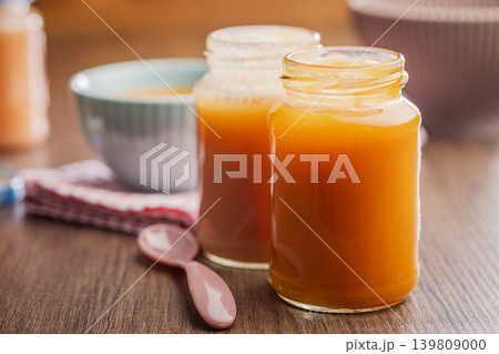 Creamy Carrot Baby Food Puree in Glass Jars With Bowl and Spoon on Wooden Table Creamy Carrot Baby Food Puree in Glass Jars With Bowl and Spoon on Wooden Table 139809000