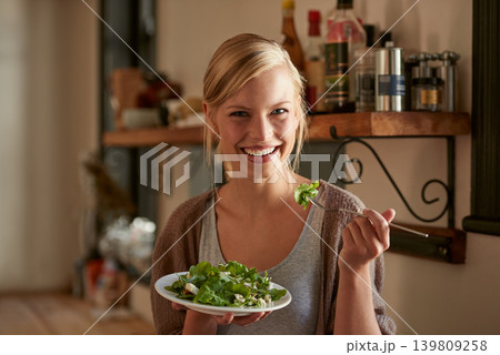Portrait, happy woman and eating salad in kitchen at home, nutrition and leafy greens for healthy diet. Vegetables, bowl and face of hungry person with food, fork and organic vegan meal for wellness Portrait, happy woman and eating salad in kitchen at home, nutrition and leafy greens for healthy diet. Vegetables, bowl and face of hungry person with food, fork and organic vegan meal for wellness 139809258