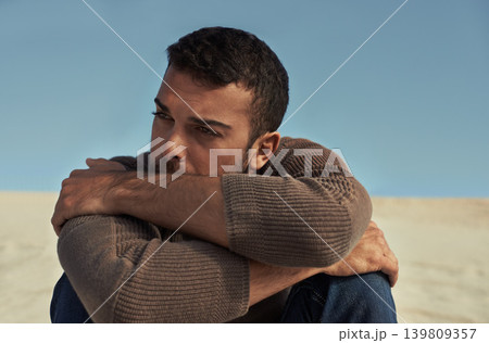Depressed, model or man in the desert thinking of travel in summer sitting on holiday vacation. Upset, worry or stress with face of nervous person on the ground or sand dunes with anxiety or fear Depressed, model or man in the desert thinking of travel in summer sitting on holiday vacation. Upset, worry or stress with face of nervous person on the ground or sand dunes with anxiety or fear 139809357