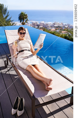 Woman, happy and magazine on sunbed by pool with sunglasses for relax, article or lifestyle news. Person, champagne and paper outdoor on holiday, vacation or summer trip at hotel or resort with smile Woman, happy and magazine on sunbed by pool with sunglasses for relax, article or lifestyle news. Person, champagne and paper outdoor on holiday, vacation or summer trip at hotel or resort with smile 139809402