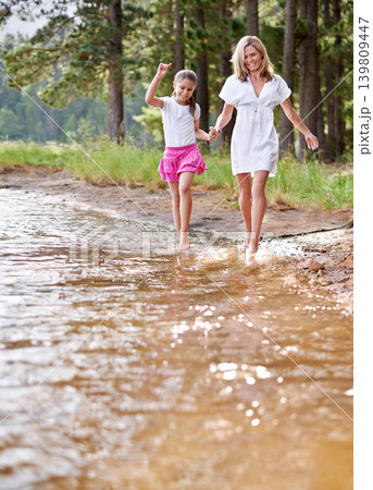 Mother, daughter and happiness outdoor in river for bonding, support or holding hands on holiday in nature. Family, woman and girl child with smile or adventure on vacation, travel and lake with love Mother, daughter and happiness outdoor in river for bonding, support or holding hands on holiday in nature. Family, woman and girl child with smile or adventure on vacation, travel and lake with love 139809447