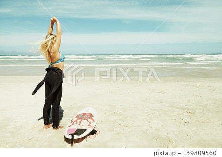 Sports, stretching and woman on beach with surfboard for travel, vacation or holiday on tropical coast. Earth, nature and sky with surfer on sand by sea or ocean for hobby or leisure from back Sports, stretching and woman on beach with surfboard for travel, vacation or holiday on tropical coast. Earth, nature and sky with surfer on sand by sea or ocean for hobby or leisure from back 139809560