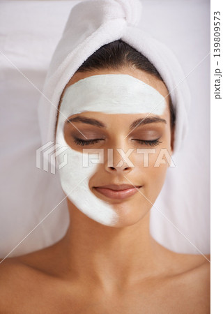 Woman, face mask and wellness with skincare in spa, detox and cosmetic treatment for kaolin facial. Person, relax and beauty with natural clay on skin, soothing and cleaning with dermatology on bed 139809573