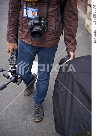 Lighting, equipment and photographer in outdoor for photoshoot with camera lens and gear. Cameraman, walking and photography tools for press, project and person travel on street with reflector tech Lighting, equipment and photographer in outdoor for photoshoot with camera lens and gear. Cameraman, walking and photography tools for press, project and person travel on street with reflector tech 139809574