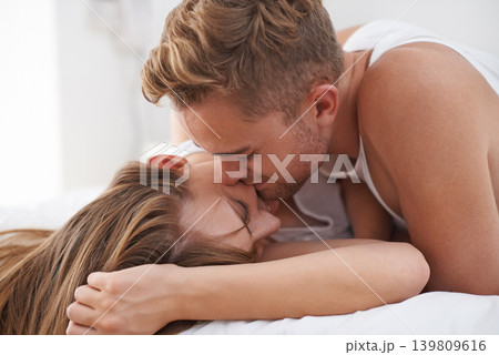 Couple, morning and bed in love with kiss and happy together in marriage. Weekend, getaway and bonding in house with care and lovers cuddle for affection and partners with commitment in apartment 139809616