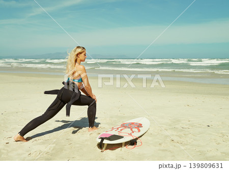Training, stretching and woman on beach with surfboard for sports, exercise or fitness in summer. Health, travel and view of water with young surfer person getting ready on sand by sea or ocean 139809631