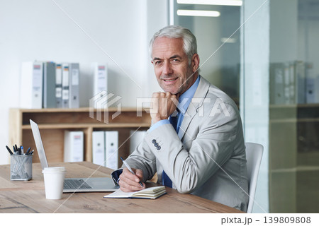 Senior, businessman and smile, laptop and portrait at desk in the office for consultation. CEO, man and plan for budget, payroll and human resources and writing in company for startup proposal Senior, businessman and smile, laptop and portrait at desk in the office for consultation. CEO, man and plan for budget, payroll and human resources and writing in company for startup proposal 139809808