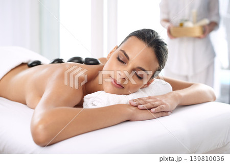 Nap, hot stone and woman with massage at spa for wellness, health and back treatment. Self care, cosmetic and young female person sleeping for warm rock skin therapy at natural beauty salon. Nap, hot stone and woman with massage at spa for wellness, health and back treatment. Self care, cosmetic and young female person sleeping for warm rock skin therapy at natural beauty salon. 139810036