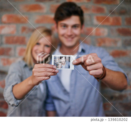 Hands, photograph and couple on wall blurred background together for love, bonding of memory of past. Portrait, smile or happy with young man and woman holding picture for romance or nostalgia Hands, photograph and couple on wall blurred background together for love, bonding of memory of past. Portrait, smile or happy with young man and woman holding picture for romance or nostalgia 139810202