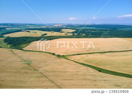 Aerial landscape view of yellow cultivated agricultural field with ripe wheat on bright summer day Aerial landscape view of yellow cultivated agricultural field with ripe wheat on bright summer day 139810908
