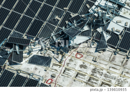 Destroyed by hurricane winds broken down photovoltaic solar panels mounted on industrial building roof for producing green ecological electricity. Consequences of natural disaster in Florida 139810935