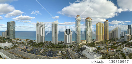 Aerial view of Sunny Isles Beach city with luxurious highrise hotels and condos on Atlantic ocean shore. American tourism infrastructure in southern Florida Aerial view of Sunny Isles Beach city with luxurious highrise hotels and condos on Atlantic ocean shore. American tourism infrastructure in southern Florida 139810947