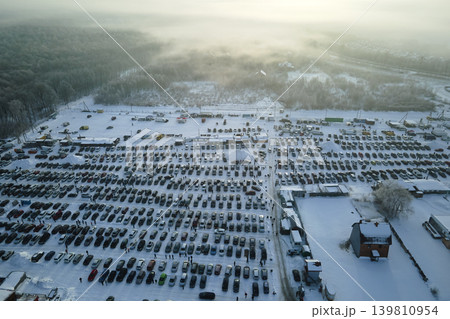Aerial view of many cars parked for sale and people customers walking on car market or parking lot in winter Aerial view of many cars parked for sale and people customers walking on car market or parking lot in winter 139810954