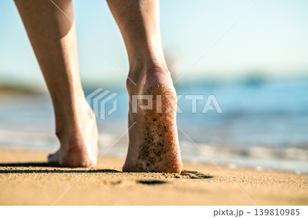 Close up of woman feet walking barefoot on sand leaving footprints on golden beach. Vacation, travel and freedom concept. People relaxing in summer. 139810985