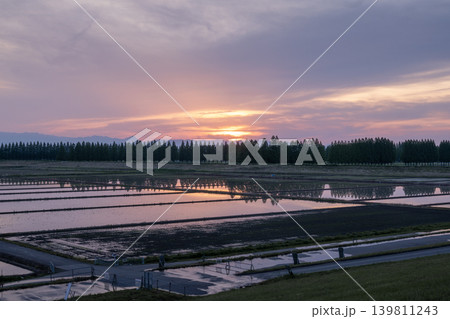 夕暮れ時に水田に広がる美しい夕焼けの映り込みと農村風景 139811243