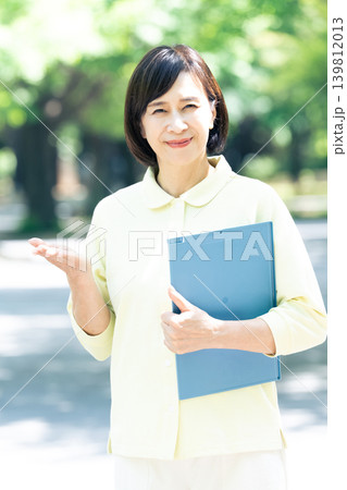 屋外でバインダーを持つ介護職の女性 139812013