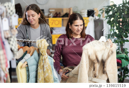 During November sales, Latin woman choose fur coat, other client in background 139815519