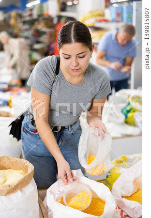 Young woman purchaser buying crushed corn in supermarket Young woman purchaser buying crushed corn in supermarket 139815807