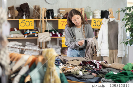 During November sales, young woman choose and buy trousers 139815813