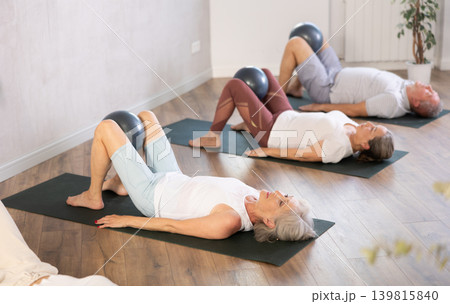 Group of elderly people doing pilates with soft ball in studio 139815840