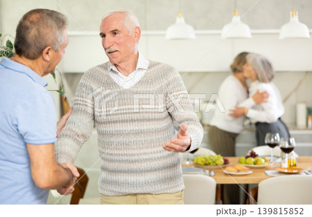 Two elderly men shaking hands in kitchen Two elderly men shaking hands in kitchen 139815852
