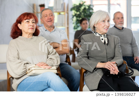 Interested group of people of different ages sitting on chairs and listening lecture in conference hall Interested group of people of different ages sitting on chairs and listening lecture in conference hall 139816027