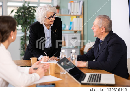 Senior business community listening to female speaker or presenter during round table conference. Senior business community listening to female speaker or presenter during round table conference. 139816146