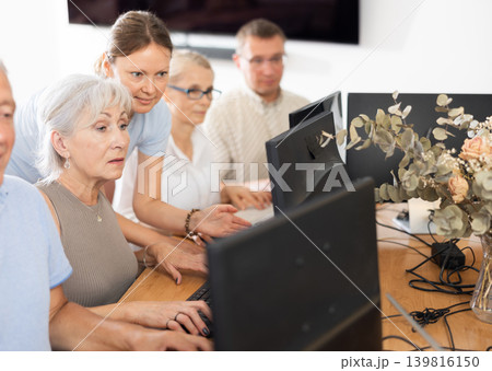 Young female mentor explaining something to elderly woman at computer lesson Young female mentor explaining something to elderly woman at computer lesson 139816150