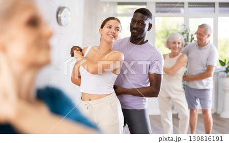 Girl teacher dances pair dance with african male student of fitness class Girl teacher dances pair dance with african male student of fitness class 139816191