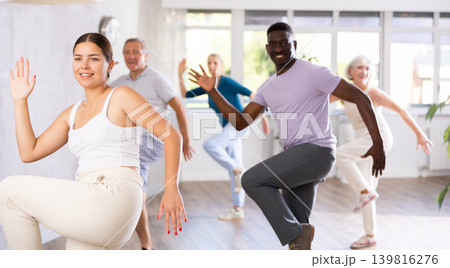 Female instructor teaches mature students of dance class basic movements of hip hop dance 139816276