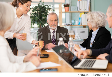 Elderly man leading meeting with senior colleagues at table Elderly man leading meeting with senior colleagues at table 139816301