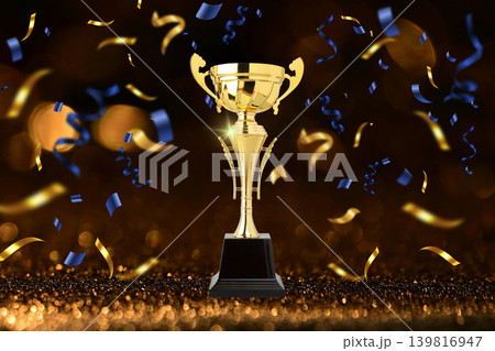 Golden trophy stands tall with colorful confetti around it 139816947