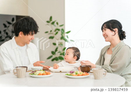 食卓で赤ちゃんに離乳食,ご飯を食べさせる母親と父親（育児・子育て） 139817459