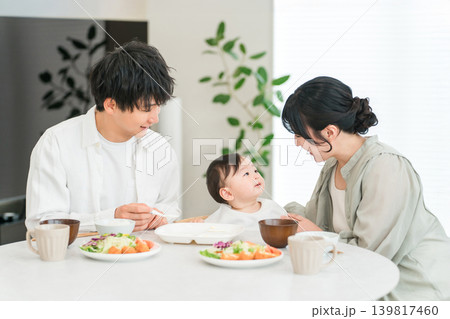 食卓で赤ちゃんに離乳食,ご飯を食べさせる母親と父親（育児・子育て） 139817460