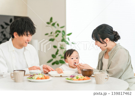 食卓で赤ちゃんに離乳食,ご飯を食べさせる母親と父親（育児・子育て） 139817462