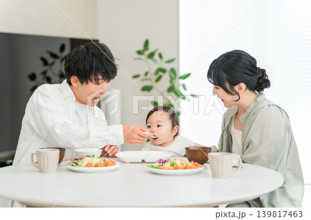 食卓で赤ちゃんに離乳食,ご飯を食べさせる母親と父親（育児・子育て） 139817463