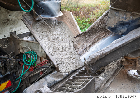 Concrete mixer truck pouring wet gray cement into a chute for an active construction project, 4 Concrete mixer truck pouring wet gray cement into a chute for an active construction project, 4 139818047