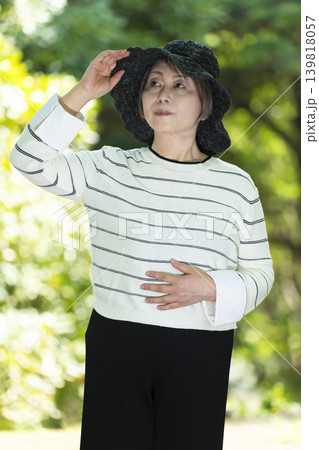 新緑の公園で帽子を被り散歩するシニア女性 新緑の公園で帽子を被り散歩するシニア女性 139818057