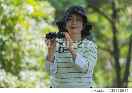 新緑の公園で双眼鏡でバードウォッチングするシニア女性 新緑の公園で双眼鏡でバードウォッチングするシニア女性 139818685