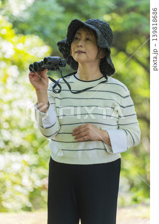 新緑の公園で双眼鏡でバードウォッチングするシニア女性 新緑の公園で双眼鏡でバードウォッチングするシニア女性 139818686