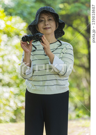 新緑の公園で双眼鏡でバードウォッチングするシニア女性 139818687