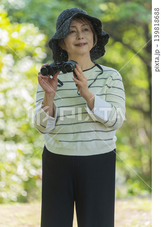 新緑の公園で双眼鏡でバードウォッチングするシニア女性 新緑の公園で双眼鏡でバードウォッチングするシニア女性 139818688