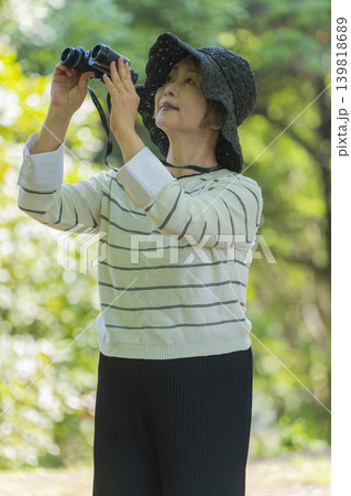 新緑の公園で双眼鏡でバードウォッチングするシニア女性 新緑の公園で双眼鏡でバードウォッチングするシニア女性 139818689