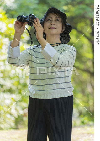 新緑の公園で双眼鏡でバードウォッチングするシニア女性 新緑の公園で双眼鏡でバードウォッチングするシニア女性 139818691