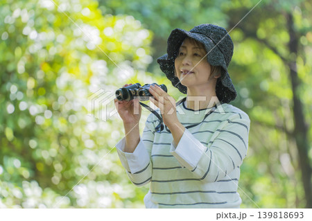 新緑の公園で双眼鏡でバードウォッチングするシニア女性 新緑の公園で双眼鏡でバードウォッチングするシニア女性 139818693