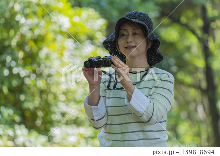 新緑の公園で双眼鏡でバードウォッチングするシニア女性 新緑の公園で双眼鏡でバードウォッチングするシニア女性 139818694