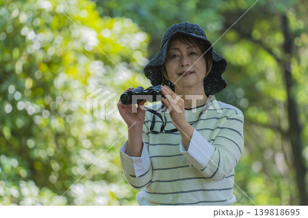 新緑の公園で双眼鏡でバードウォッチングするシニア女性 新緑の公園で双眼鏡でバードウォッチングするシニア女性 139818695