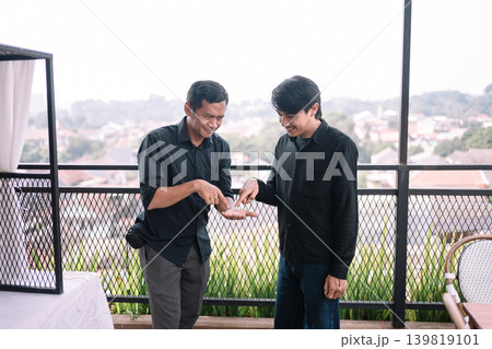 Southeast Asian male friends chatting together outside during daytime 139819101